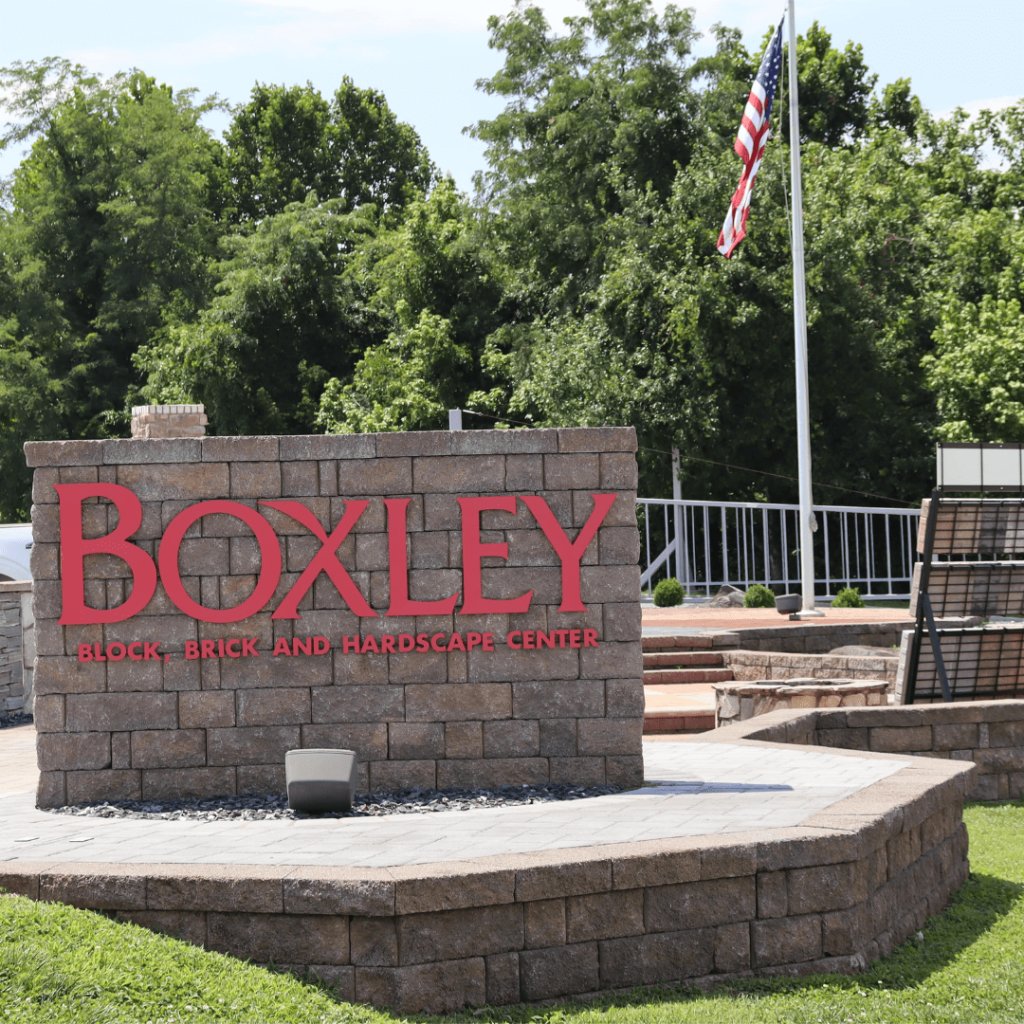 Showroom entrance sign built from retaining wall block, with a flagpole behind it